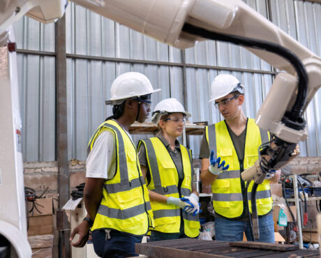 In robotic training center instructor teaching girl engineer how to operate and program robot arm